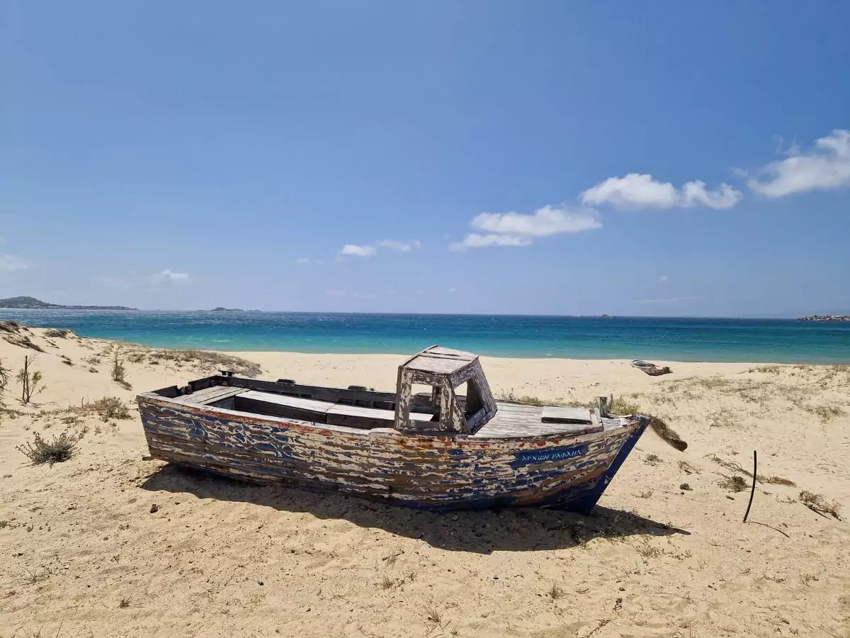 An abandoned boat on a sandy beach in Naxos 